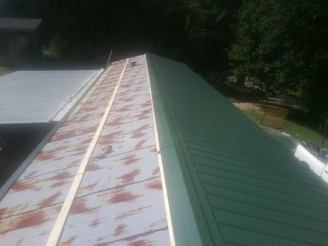 Old rusted panels beside newly installed green metal roofing — Wind Damage Roof Repair by Roofing Brothers in Deer Park