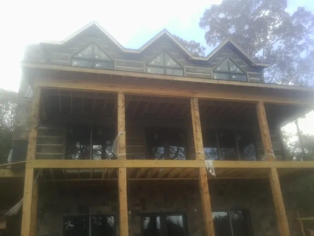 Dormers and porch framing on a large log home under construction — Roof Coating work by our crew in Deer Park