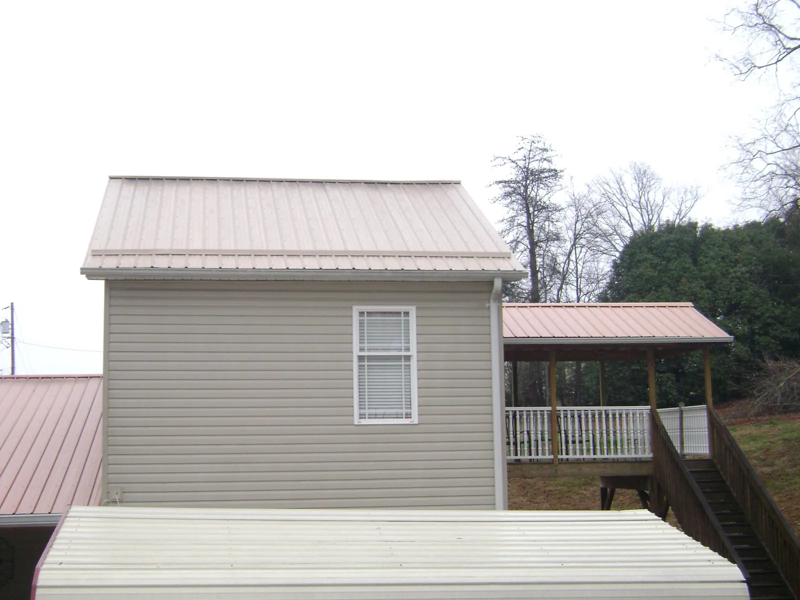 Tan metal roofs on a two story addition and attached porch, from a Roof Replacement job in Deer Park