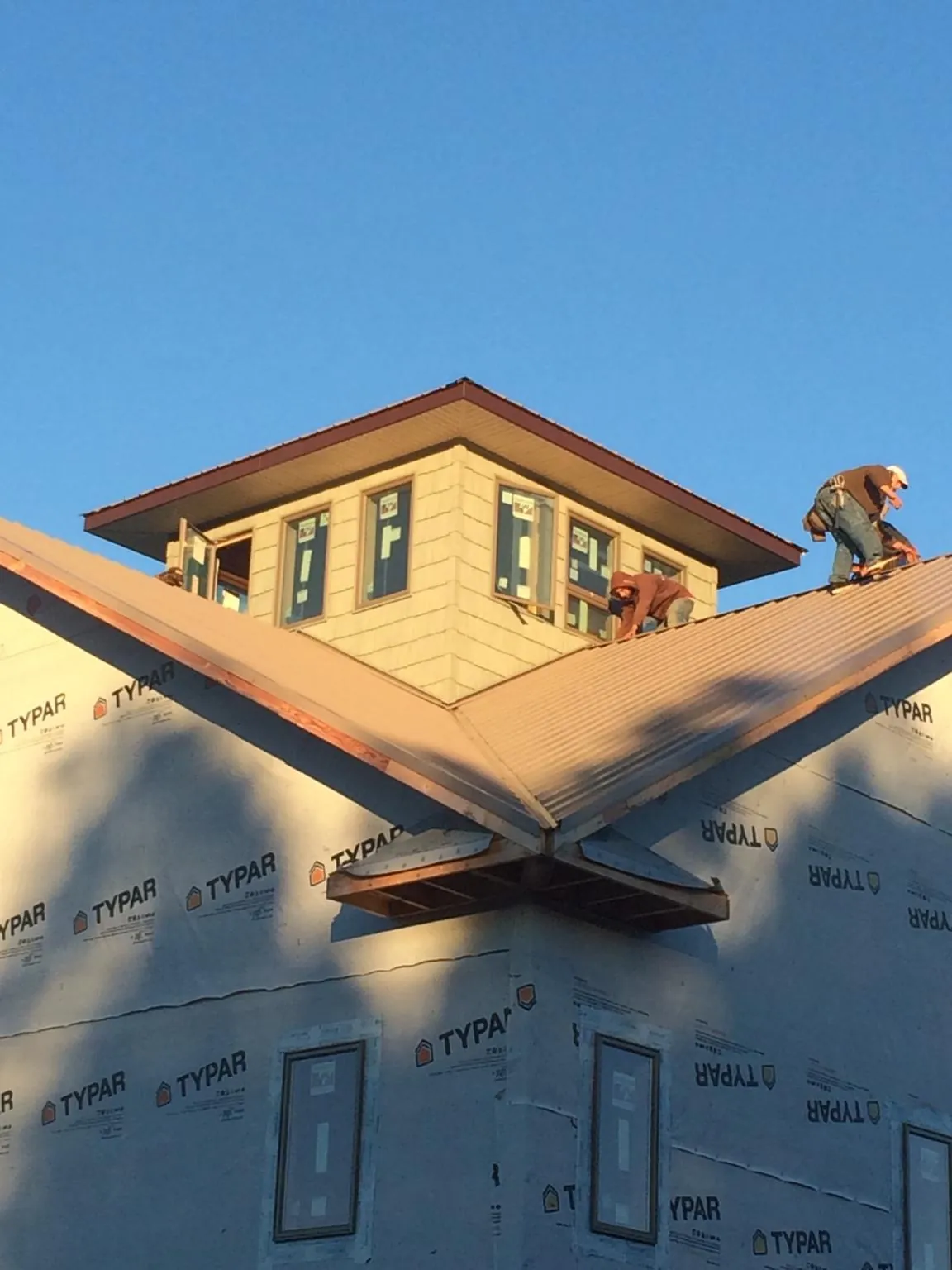 Roofers working around a rooftop cupola on a new metal roof at sunset — Roof Waterproofing in Deer Park by Roofing Brothers
